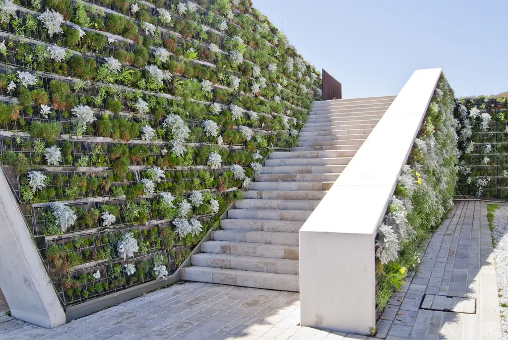 Jardin vertical en una pared inclinada junto a una escalera